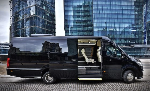 Czarny bus VIP przy szklanych biurowcach w Warszawie