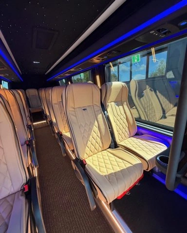 Wnętrze busa VIP z pikowanymi fotelami i niebieskim podświetleniem