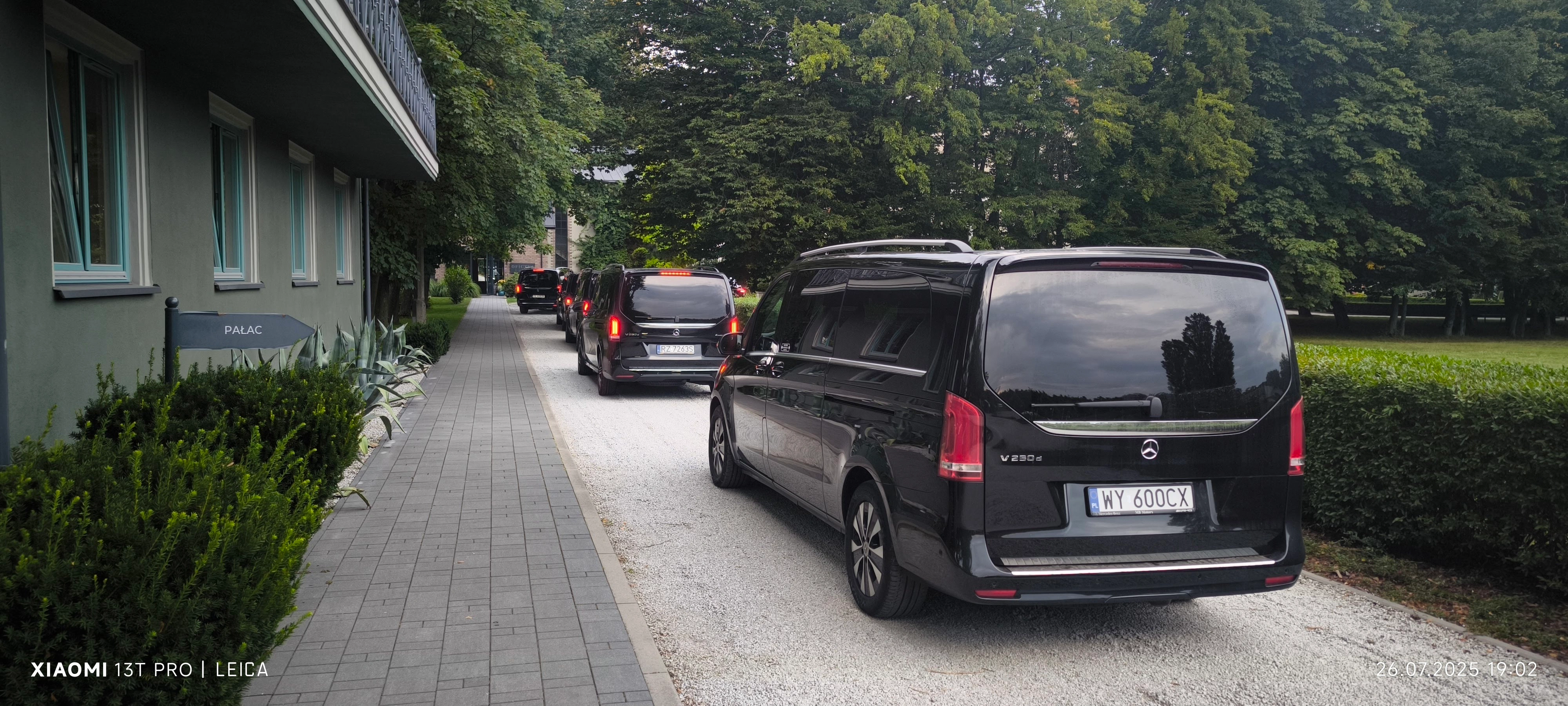 Kolumna vanów Mercedes klasy V w drodze do obiektu