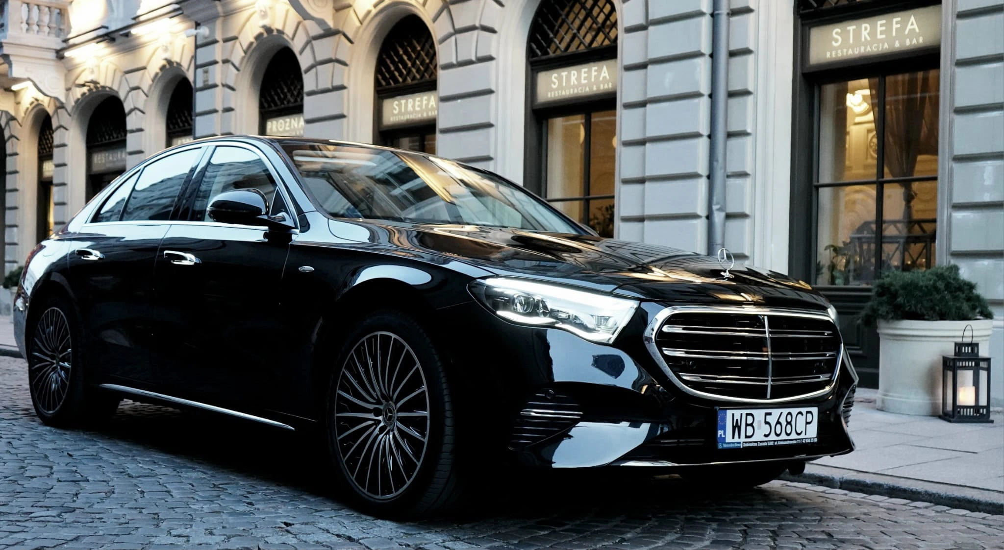 Czarna limuzyna Mercedes klasy S zaparkowana przed kamienicą w centrum Warszawy